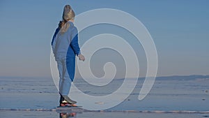 The girl train on ice speed skating. The child skates in the winter in blue sportswear suit, sport glasses. Children