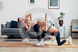 Girl trains with her mother at home, doing side bends