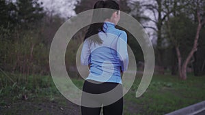 Girl trains outdoors. jogging. A young girl in blue sports clothes is running along the evening park. back view. female