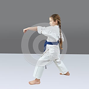 Girl trains a punch hand on a gray background