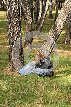 Girl with a trash bag picks up trash in the forest, environmental protection, pollution control