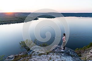 Girl travel in mountains alone. Backpacker walking outdoors, view over river valley landscape in sunlight