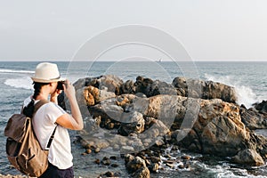 Girl traveler with a backpack and camera on the beach