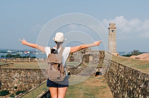 Girl traveler with a backpack. City clock tower in the town