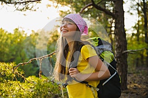 Girl traveler with backpack in hill forest. Adventure, travel, tourism concept