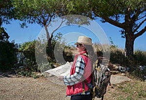 Girl traveler with a backpack and a map goes along the route. Hiking