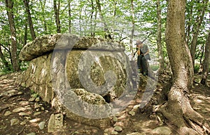 Girl traveler sits near ancient megalithic dolmen