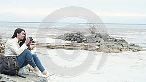 girl traveler sitting on rocks taking pictures on a vintage camera landscapes