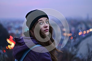 Girl traveler standing in front of winter evening cityscape