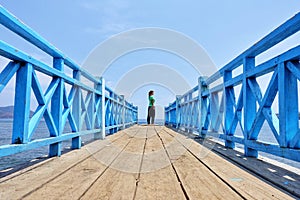 Girl Traveler Standing On a Wooden Pier Gazing Into the Distance