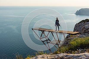 A girl traveler stands on the edge of a cliff on the bridge