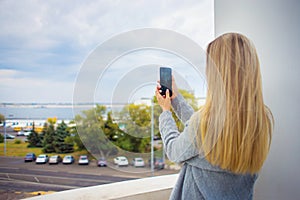 A girl traveler takes on the phone an overview of a big city with a river view. City landscape. Technology application