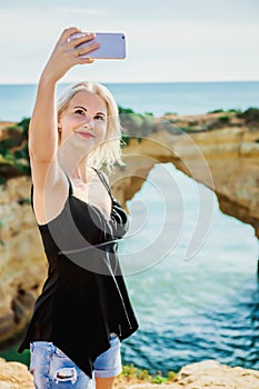 Girl traveller make selfie on background of sea and cliffs