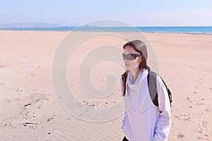 Girl traveller walks on sea sand empty beach off-season in dunes on vacation.
