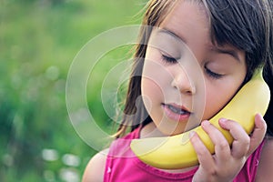 The girl tries to speak by means of a banana instead of phone.