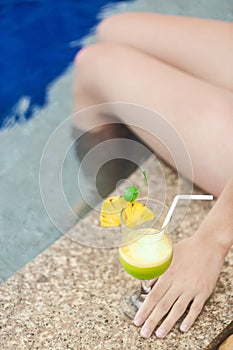 Girl with tropical cocktail on the pool