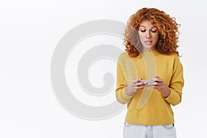 Girl trying carefully pass level, standing determined and focused, make intense look on mobile display, holding