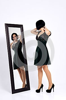 Girl trying on short dress and looking at herself  in the mirror