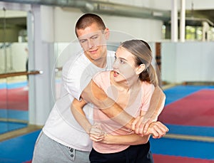 Girl trying to escape rear grab attack striking ribs with elbow during self defense course