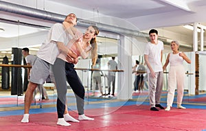Girl trying to escape rear hug of male opponent, striking with elbow to chin
