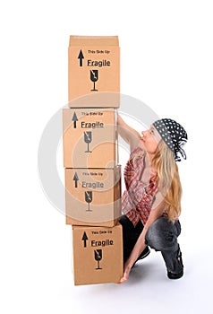 Girl trying to lift a stack of cardboard boxes