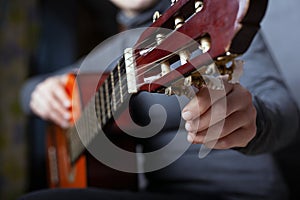 Girl tunes an acoustic guitar close-up. playing a musical instrument