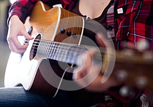 Girl tuning guitar. Focus on strings of guitar