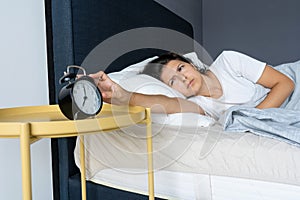 The girl turns off the annoying alarm clock to continue sleeping. Get some more sleep. It is a hard morning. Time to wake up