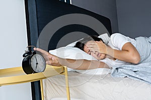 The girl turns off the annoying alarm clock to continue sleeping. Get some more sleep. It a hard morning. Time to wake up