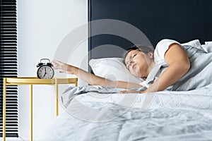 The girl turns off the annoying alarm clock to continue sleeping. Get some more sleep. It s a hard morning. Time to wake up