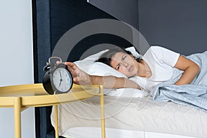 The girl turns off the annoying alarm clock to continue sleeping. Get some more sleep. It s a hard morning. Time to wake up