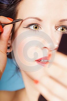 Girl tweezing eyebrows closeup