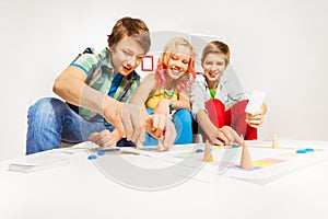 Girl and two boys playing table game at home