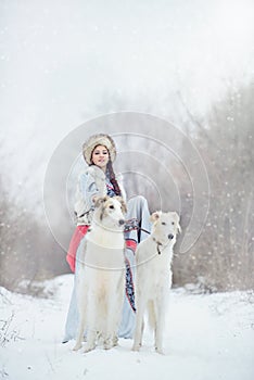 Girl with two greyhounds walking in the winter