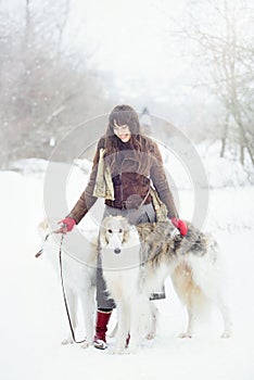 Girl with two greyhounds in winter, falling snow