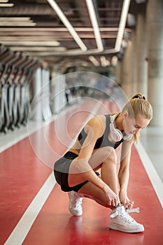 Girl tying shoelaces at fitness gym before running exercise workout for cardio