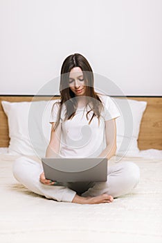 Girl typing on laptop sitting on sofa. Girl freelancer working on laptop in home