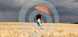 Girl with umbrella at field. in storm