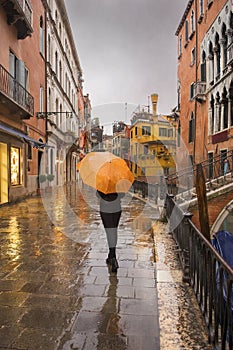 Girl with umbrella on promenade of Venice during a rain