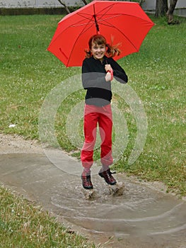 Girl with umbrella on puddles