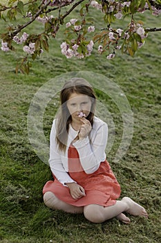 A girl under a blooming tree over green grass background