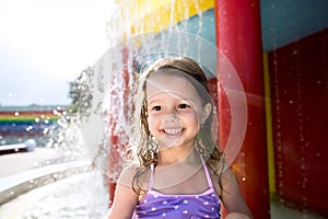 Girl under splashing fountain. Summer heat and water.