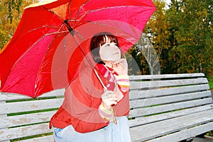 Girl under an umbrella on an old bench.