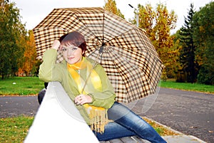 Girl under an umbrella on an old bench.