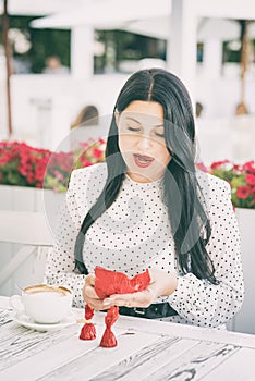 The girl unfolds the candies with amazement and delight. A girl in a cute dress unfolds and eats candy