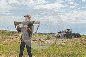 Girl in uniform with a Bazooka on the background of a broken tan