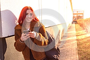 A portrait of a happy female college student using smartphone at campus.