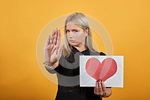 Girl upset unhappy woman holding piece of paper with red heart palm hand stops