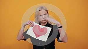 Girl upset unhappy woman holding piece of paper with red heart palm hand stops