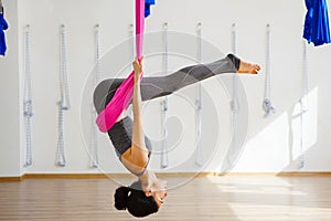 Girl in upside down inversion pose on pink silk hammock